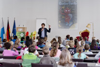 Viele Kinder sitzen an Tischen und verfolgen einen Vortrag bei der Kinderuni