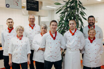 acht Mitarbeitende bei Swiss Life mit weißen Kochjacken und roten Halstüchern