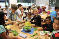 fünf Schulkinder bereiten im Klassenraum gemeinsam Essen zu