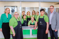 zehn Mitarbeitende der Katerine GmbH am Jules Verne Campus mit grünen Poloshirts in der Küche