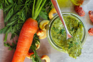 Glas mit grünem Pesto mit Karotte und Möhrengrün
