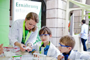 Zwei Kinder experimentieren und führen Versuche durch unter Anleitung einer Frau