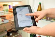 vor einem offenen Kühlschrank halten Hände ein Tablet, auf der die stocky-App zu sehen ist.