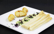 Ein Teller mit weißem Spargel, Kartoffeln und heller Sauce, garniert mit Kresse