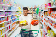 Mann vergleicht Produkte im Supermarkt