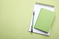 Notizblock und Stift auf hellgrünem Hintergrund