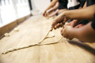 Schülerinnen und Schüler formen Laugenzöpfe auf einer hölzernen Arbeitsfläche