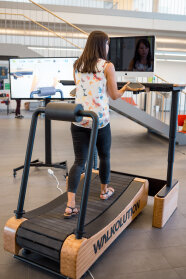 Frau auf geht auf einem speziellen Laufband und arbeitet dabei am Computer