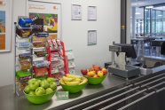 Obstschalen mit Äpfeln und Bananen stehen vor dem Süßigkeitenständer