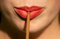 Rot geschminckte Lippen halten einen Trinkhalm