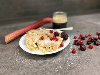 Crumble auf Teller mit roten Beeren garniert