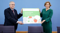 Bundesministerin Klöckner und Prof. Güllner halten eine Platte mit dem Cover des Ernährungsreports 2021 in die Kamera
