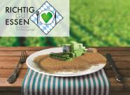 Logo der Ernährungstage 2017: Ein Miniatur-Mähdrescher im Weizenfeld auf einem Teller, der auf einem Tisch steht