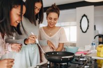 Drei Mädchen stehen an einem Herd und kochen gemeinsam