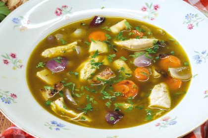 Hühnersuppe mit Karotten und Zwiebeln in einem Suppenteller angerichtet