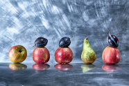 Äpfel, Zwetschgen und eine Birne liegen auf einer Edelstahlplatte.